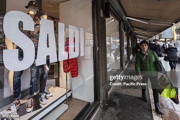 Woman walks past a shop window offering discounts during the winter sales in downtown Rome, Italy. The first day of winter sales in many Italian...