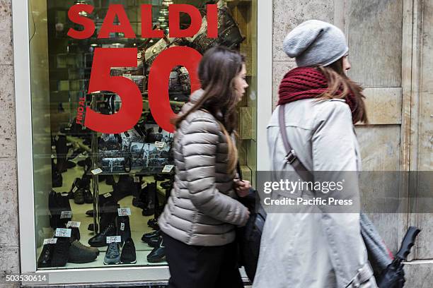 People walk past a shop window offering generous discounts during the winter sales in downtown Rome, Italy. The first day of winter sales in many...