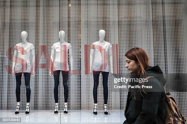 Woman walks past a shop window offering discounts during the winter sales in downtown Rome, Italy. The first day of winter sales in many Italian...