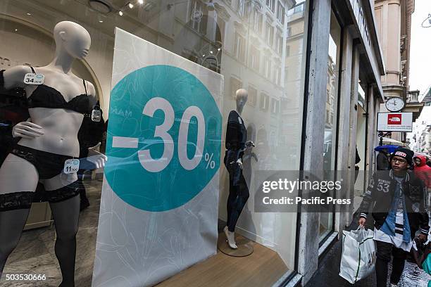 Man walks past a shop window offering generous discounts during the winter sales in downtown Rome, Italy. The first day of winter sales in many...