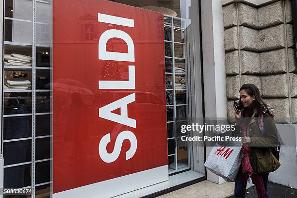 Woman walks past a shop window offering discounts during the winter sales in downtown Rome, Italy. The first day of winter sales in many Italian...