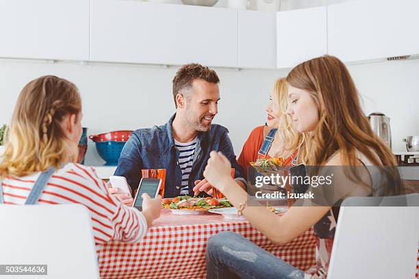 teenager girl using smart phone during lunch with family - teenagers eating with mum stock pictures, royalty-free photos & images