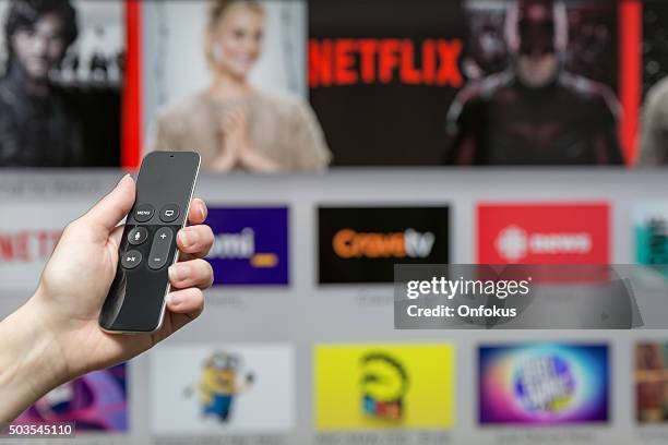 human hand holding the new apple tv siri remote - netflix stockfoto's en -beelden