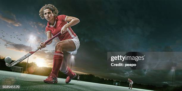 field hockey player in mid action during hockey game - hockey stockfoto's en -beelden