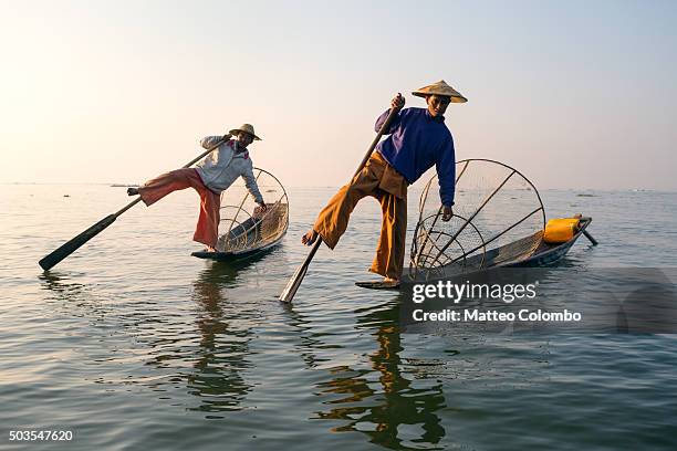 two local intha fishermen fishing on inle lake, at sunrise - myanmar culture stockfoto's en -beelden