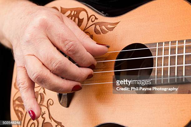 woman's hand plucking a ukulele - ukelele stock pictures, royalty-free photos & images