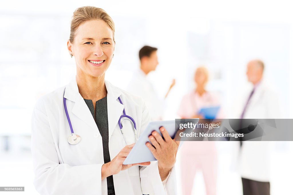 Smiling Female Doctor Using Tablet Computer In Hospital