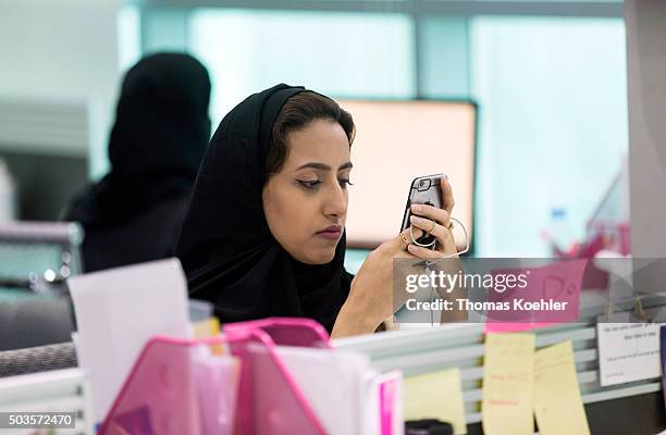 Riad, Saudi Arabia A young Arab woman looking at her smartphone in the employment agency for women 'Glowork' on October 19, 2015 in Riad, Saudi...