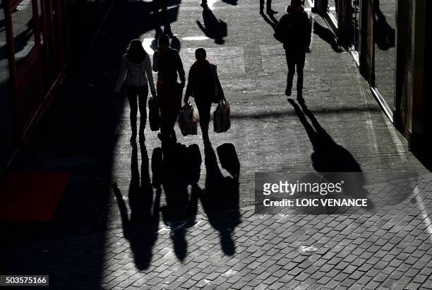 People walk as they holding shopping bags bags during the first day of national winter sales, on January 6, 2015 in Nantes, western France. / AFP...