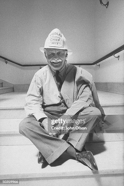 Boston Pops conductor Arthur M. Fielder wearing one of his collection of 400 firemen's helmets.