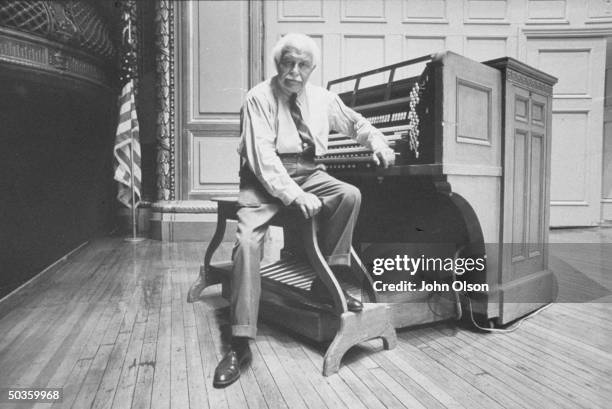 Boston Pops conductor Arthur M. Fiedler sitting at the keyboard of a large organ.