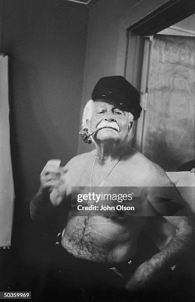 Boston Pops conductor Arthur M. Felder posing with a flower and hat in his dressing room before a performance.