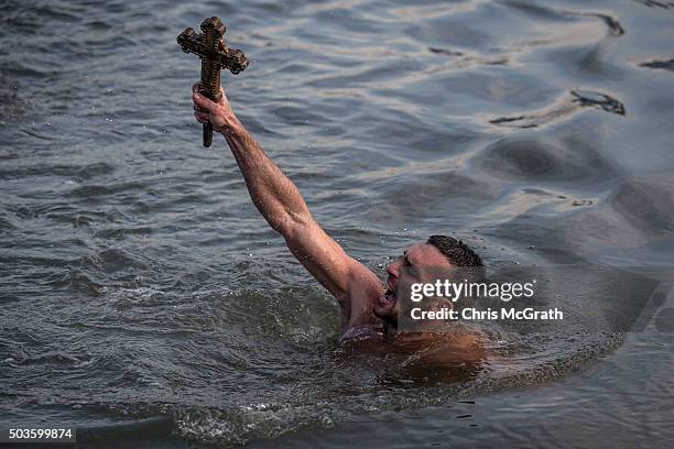 Greek Orthodox swimmer Nico Solis holds up a wooden cross after retrieving it from the Bosphorus river during the blessing of the water ceremony, as...