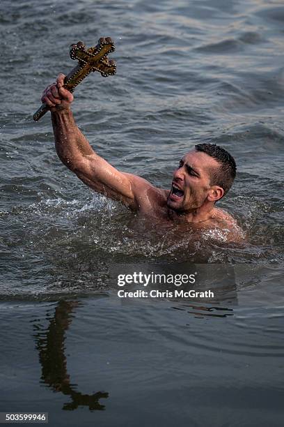 Greek Orthodox swimmer Nico Solis holds up a wooden cross after retrieving it from the Bosphorus river during the blessing of the water ceremony, as...