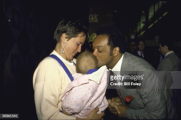 Presidential primary candidate Rev. Jesse L. Jackson leaning down to kiss a baby during his campaign.