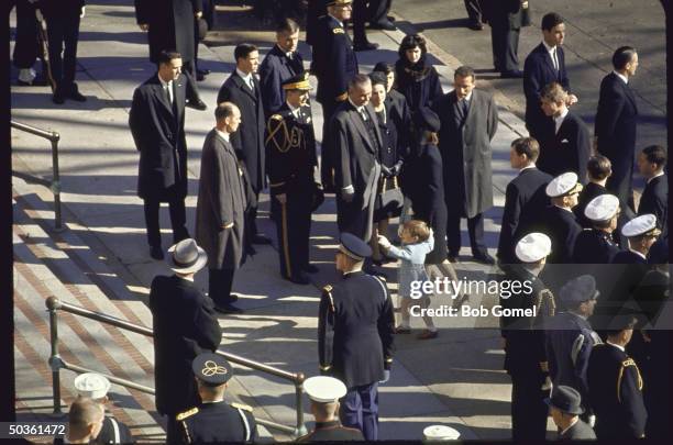 President Johnson and Lady Bird Johnson greet Jacqueline Kennedy with John Jr. And Caroline outside St. Mathews Cathedral before the start of requiem...