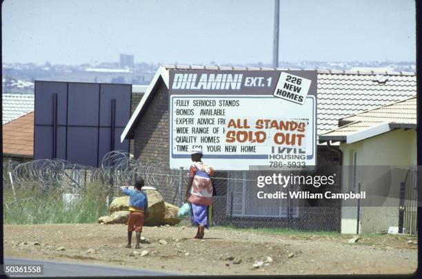 Billboards advertising good deals in building new homes, re apartheid law limiting mobility of Blacks, scrapped in 4/86.
