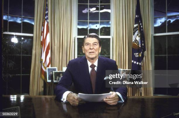 President Ronald W. Reagan seated at desk in Oval Office.