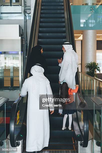 arabian family on a shopping mall's escalator. - saudi grandfather stock pictures, royalty-free photos & images