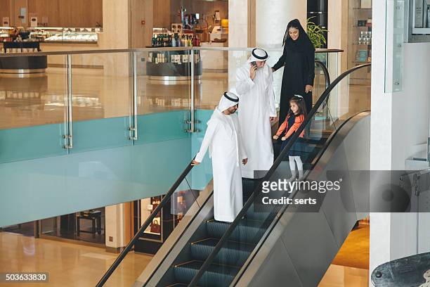 arabian family on a shopping mall's escalator. - dubai cares stock pictures, royalty-free photos & images