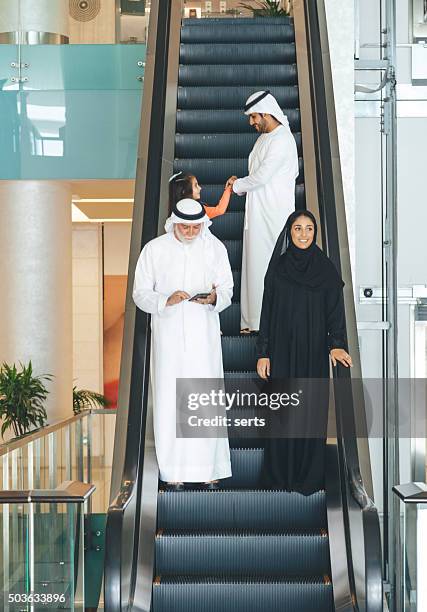 arabian family on a shopping mall's escalator. - saudi grandfather stock pictures, royalty-free photos & images