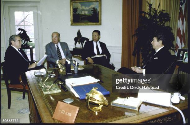 Pres. Ronald W. Reagan seated at his desk in Oval Office, discussing the upcoming summit with Soviet leader Mikhail S. Gorbachev with WH Chief of...