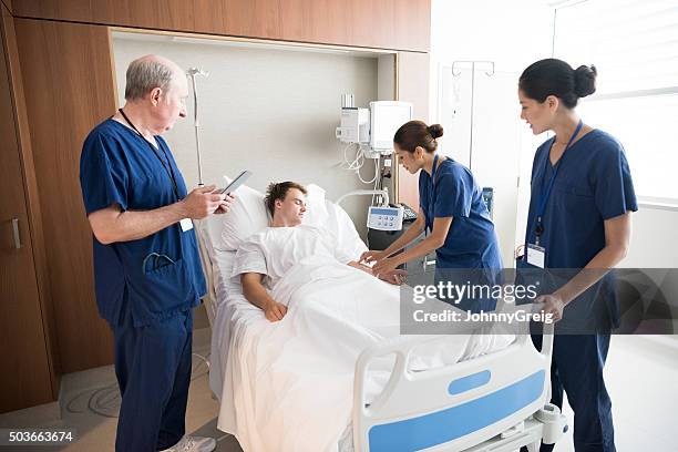medical team treating male patient in hospital bed - hospital room stock pictures, royalty-free photos & images