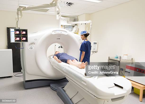 radiologist watching patient in cat scanner in hospital - ct scanner stockfoto's en -beelden