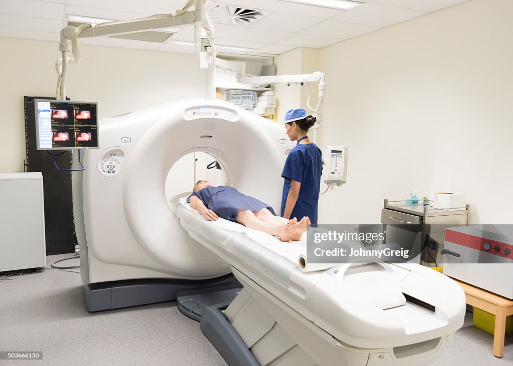 Radiologist watching patient in CAT scanner in hospital