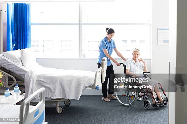 mature woman in wheelchair with nurse in hospital room - help australia stock pictures, royalty-free photos & images