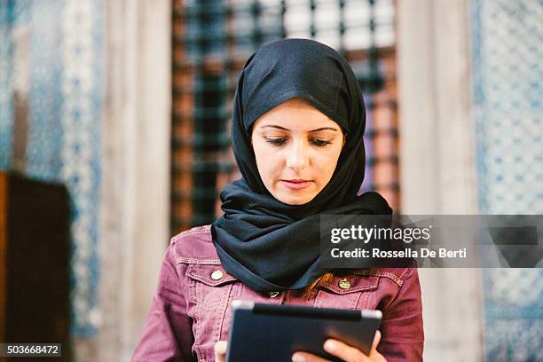 retrato de una mujer joven usando tableta al aire libre con pañuelo de cabeza - arab businesswoman with books fotografías e imágenes de stock