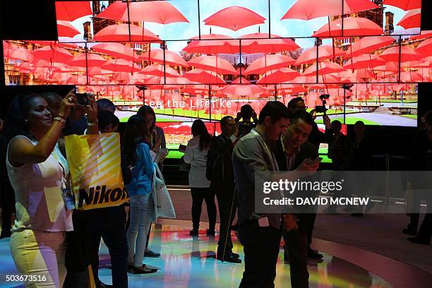 People watch a large video display of Samsung SUHD TV Quantum dot display screens at the CES 2016 Consumer Electronics Show in Las Vegas, Nevada on...