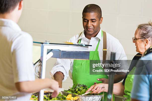 cafeteria worker serviert gesunde speisen für studenten in mittagessen line - kantinenfrau stock-fotos und bilder