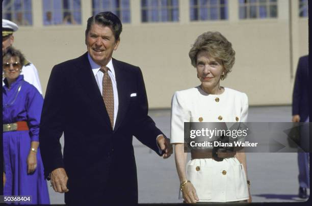 Secret servicemen walking alongside President Ronald W. Reagan and his wife as they deplane Marine One helicopter upon returning from their vacation.