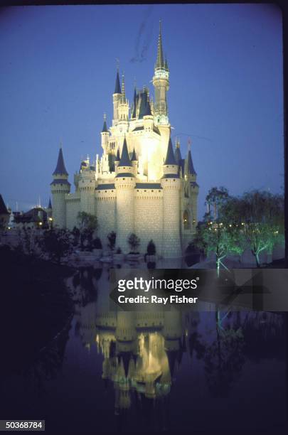 Disney World in Florida: the exterior of Cinderella's Castle lit up at night and reflected in an artificial stream, Florida, USA, 1971.