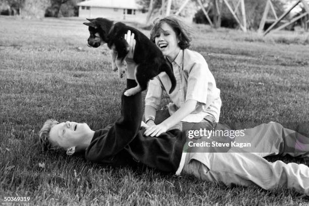 Actors Anthony Michael Hall and Molly Ringwald playing w. Puppy during break in location shooting of The Breakfast Club.