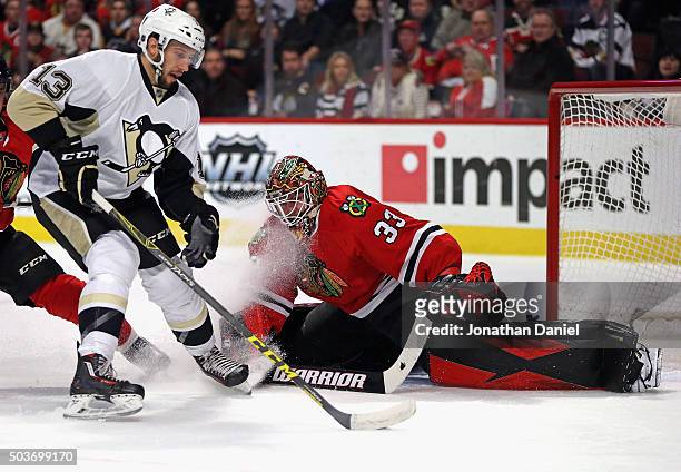 Scott Darling of the Chicago Blackhawks sprawls to make a save against Nick Bonino of the Pittsburgh Penguins at the United Center on January 6, 2016...