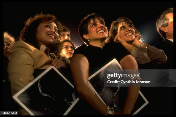 Rapt faces of women holding pics of Pres. Bill Clinton in crowd of his supporters at Unity '96 election campaign rally at Universal Studios.