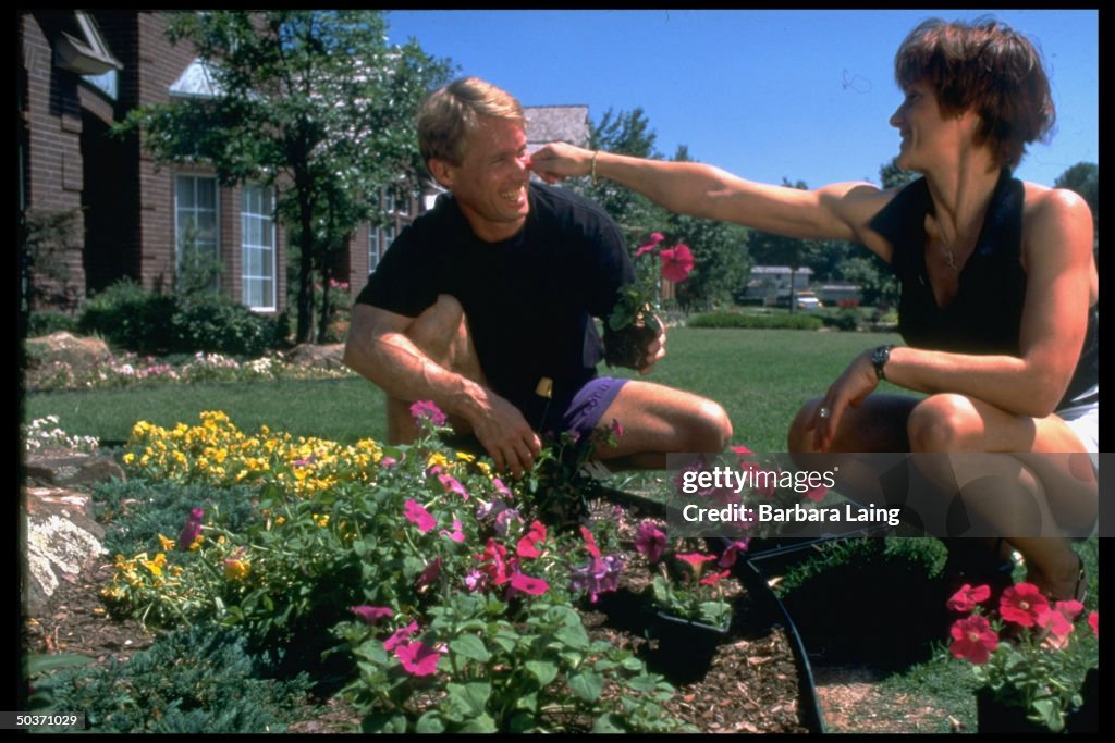 Married gold medalist gymnasts Bart Conner & Nadia Comaneci crouching