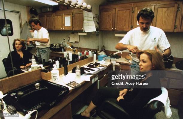 Gillian Anderson, co-star of cult TV series The X-Files, getting hair done by unident. Male stylist in dressing room on the set of the show.