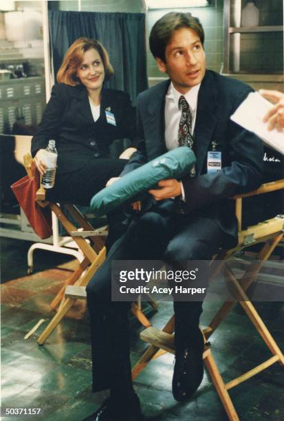 Gillian Anderson & David Duchovny, co-stars of cult hit TV series The X-Files, sitting in directors' chairs in between filming on the set of the show.