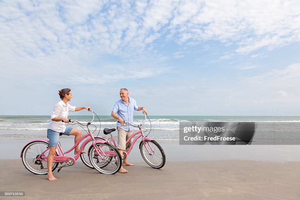 Älteres Paar Reiten Fahrräder im Freien am Strand bei Sonnenuntergang