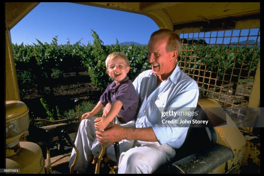 Former TV comic/vintner Tom Smothers sitting w. son Bo on lap while