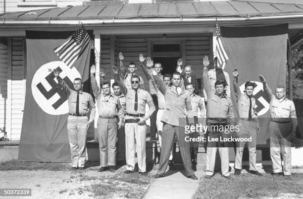 George Lincoln Rockwell , head of the American Nazi Party, and group of followers in uniform giving Heil Hitler salute in front of headquarters with...