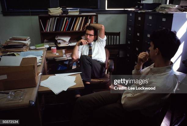 Linguistic expert and political activist Noam Chomsky , smoking pipe, sitting in his office probably with student.