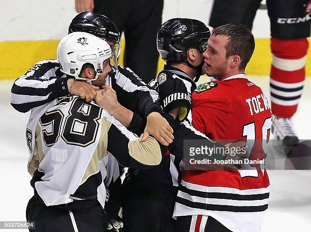 Referees get between Kris Letang of the Pittsburgh Penguins and Jonathan Toews of the Chicago Blackhawks during an altercation in the third period at...