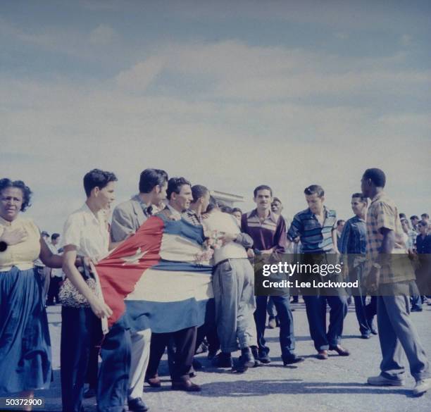 Jubilant population gathering on Havana street w. Cuban flag held proudly as victorious Castro and rebel army head toward city.