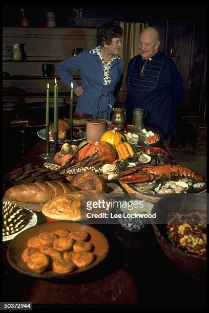 Julia Child and James Beard appear in good humor standing behind table arrayed w. Autumnal foods while appearing on TV show Revolutionary Recipes.