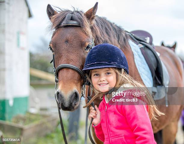 young girl enjoying horse riding lesson - paarden stockfoto's en -beelden