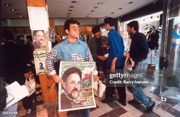 Posters picturing surprise front-runner presidential candidate Mohammed Khatami framing & displayed by youthful supporter of moderate cleric during...